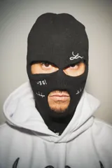 Hoodie blanco con pasamontañas negro incorporado, corte oversize, estampado en el pecho y mangas, y bolsillo tipo canguro.