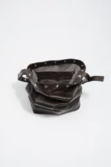 Bolso de hombro tipo tote de Bimba y Lola, confeccionado en piel vacuna con acabado brillante. Presenta un diseño estructurado con asa larga decorada con tachas metálicas plateadas y cierre de botón a presión.