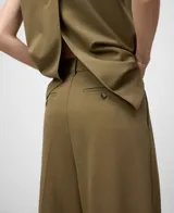 Pantalón de vestir ancho color caqui, con pinzas delanteras, trabillas en la cintura y bolsillos laterales y de vivo traseros.