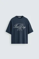 Camiseta de manga corta, cuello redondo y calce relajado, confeccionada en tejido con estructura waffle de color azul marino. Presenta estampados y bordados combinados a contraste en el delantero con texto en blanco.