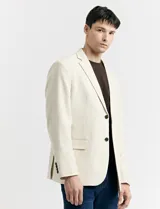 Saco beige de lino con corte clásico, solapas de muesca, cierre de dos botones, bolsillos laterales con solapa y bolsillo en el pecho.