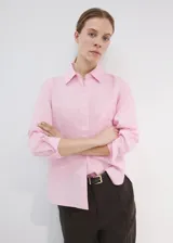 Camisa de lino color rosado, con diseño recto, cuello camisero, manga larga con puños abotonados y cierre frontal de botones.