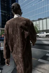 Abrigo marrón de gamuza con cuello redondo, manga larga, bolsillos delanteros y cierre frontal con botones.