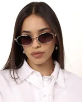 Lentes de sol con marco ovalado plateado y cristales oscuros. Ofrecen protección UV400 y son polarizados.