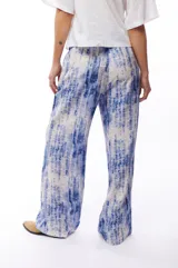Pantalón fluido con estampado abstracto en tonos azules y blancos, con bolsillos laterales.