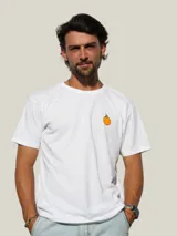 Remera de algodón blanca con cuello redondo y manga corta, presenta un pequeño estampado de un fruto de mburucuyá en el lado izquierdo del pecho.