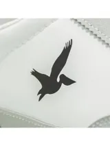 Championes deportivos Santa Barbara modelo Roam, de color blanco con detalles en gris claro y suela de goma marrón. Presentan el logotipo de la marca con la silueta de un ave en color negro en el lateral y cordones grises.