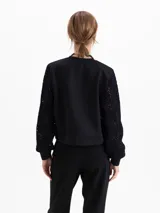 Buzo de calce regular con cuerpo de tela lisa y mangas largas de tejido calado con textura. Presenta escote redondo y puños ajustados.