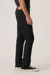 Jean de corte slim fit, color negro, con diseño clásico de cinco bolsillos, cierre de botón y cremallera, y tiro bajo.