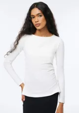 Blusa de manga larga color beige, con cuello redondo y ajuste al cuerpo, confeccionada en tejido elástico.