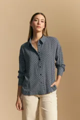 Camisa de manga larga con diseño de rayas verticales en tonos grises y blancos, cuello camisero y cierre frontal con botones.