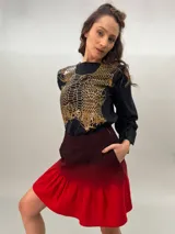 Remera negra de algodón con estampado dorado que simula un tejido o collar sobrepuesto. Presenta una moldería que realza los hombros y se entalla levemente hacia la cintura.