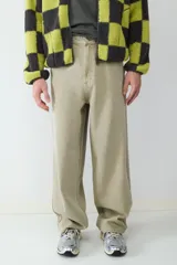Pantalón de corte holgado estilo skater, color caqui, con diseño de cinco bolsillos y cierre frontal con botón y cremallera.