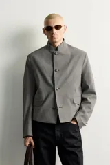 Blazer cropped de corte ajustado con estampado de cuadros, cuello mao y manga larga. Cuenta con bolsillos con solapa en la cadera y cierre frontal de botones.