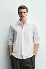 Camisa de corte regular fit color blanco, confeccionada en tejido de algodón con efecto arrugado, con cuello solapa, manga larga, puños abotonados y un bolsillo de parche en el pecho.