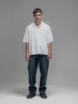 Camisa blanca de manga corta, con cuello clásico y cierre de botones frontal.