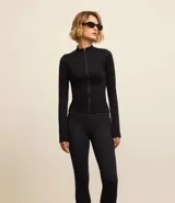 Campera deportiva negra de corte ajustado, confeccionada en tejido de poliamida seamless con textura acanalada. Tiene cuello alto y cierre frontal con cremallera.