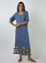 Vestido midi de algodón color azul, con mangas cortas y cuello en V con detalle de puntilla. La parte inferior presenta un diseño de crochet con motivos circulares en tonos azul, verde y beige.