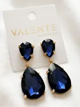 Aros colgantes con cristales facetados en forma de lágrima color azul oscuro y engarce dorado.