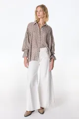 Jean color beige de corte recto, con detalles de costuras deshilachadas en los laterales y etiqueta de cuero marrón con el logo "PETRA" en la parte trasera de la cintura.