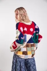 Sweater tejido a mano de lana merino, de diseño holgado con cuello redondo y mangas largas, con un colorido patrón de intarsias que representa escenas de paisajes con casas, cactus y flores.