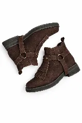 Botinetas de gamuza color marrón con suela plana de goma negra. Presentan un diseño con flecos en el empeine y una correa decorativa con herrajes metálicos dorados que es desmontable.