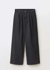 Pantalón de jean estilo wideleg color negro, con tiro medio, cierre frontal de cremallera y botón, trabillas para cinturón, bolsillos laterales y detalle de pinzas delanteras.