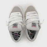 Zapatillas de skate Vision Street Wear de color beige y gris, confeccionadas en gamuza y lona, con cordones gruesos blancos y suela de goma blanca.