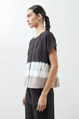 Blusa gris con estampado tie dye, de manga corta y cuello redondo con botones.