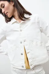Chaqueta clásica de jean color crudo, con cierre frontal de botones metálicos, bolsillos con solapa en el pecho y cuello camisero.