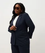 Blazer de corte sastre confeccionado en crepé, con diseño alargado y cierre frontal de doble abotonado con botones forrados. Presenta solapas clásicas y estructura recta.