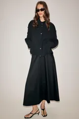 Falda midi de tiro medio en color negro, confeccionada en algodón. Presenta un diseño con pliegues verticales y cierre lateral con cremallera oculta.