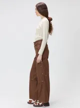 Pantalón de tiro medio y pierna ancha confeccionado en denim de algodón grueso. Presenta un diseño a rayas verticales en tonos azul y celeste, con costuras en contraste color rojo, bolsillos laterales tipo cargo y remaches metálicos.