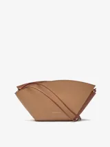 Bolso de hombro Adolfo Dominguez modelo Eclipse, confeccionado en piel bovina color tostado. Presenta un diseño estructurado formado por dos piezas asimétricas entrecruzadas, cierre con cremallera, asa de hombro extraíble y logo grabado en la parte frontal.