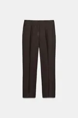 Pantalón de tiro medio confeccionado en tejido con lino, de corte recto y diseño clásico. Presenta bolsillos laterales, falsos bolsillos traseros de vivo, cierre frontal con cremallera y ganchos metálicos, y aberturas laterales en el bajo.