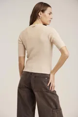 Blusa de punto acanalado color negro, con cuello alto y mangas cortas.