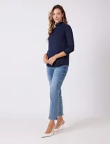 Buzo azul marino de tejido acanalado, con cuello alto tipo mock neck y mangas tres cuartos.