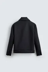 Cazadora de corte regular fit en color negro. Presenta cuello solapa con un cuello interior de punto desmontable mediante cremallera. Cuenta con cierre frontal de cremallera oculta por una solapa con botones a presión, bolsillos de plastrón con solapa en la cadera y mangas largas con puños abotonados.