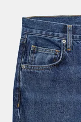 Jeans de tiro medio con corte baggy y pierna relajada. Presenta diseño de cinco bolsillos, cierre frontal con cremallera y botón, y bajo con vuelta marcada.