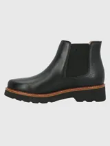 Botin tipo Chelsea de cuero negro con paneles laterales elásticos y detalle de textura en el talón. Cuenta con una suela de plataforma dentada en color negro con una franja intermedia en tono madera.