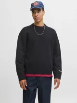 Buzo de punto de manga larga con cuello redondo y diseño holgado. Presenta puños y ruedo acanalados, con un pequeño bordado en el puño izquierdo.