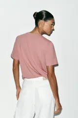 Camiseta de algodón con efecto lavado, cuello redondo y manga corta. Presenta un detalle de fornitura metálica aplicada en el pecho.