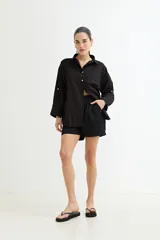 Camisa color crudo, de corte clásico, con cuello camisero, cierre frontal con botones y mangas 3/4 con trabillas.