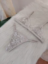 Conjunto de lencería compuesto por un bralette triangular de encaje con breteles regulables y una tanga a juego con laterales ajustables.