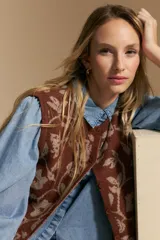 Chaleco tejido de punto con diseño floral ornamental, de silueta recta y cierre frontal con botones. Presenta una estética romántica y sofisticada, ideal para superponer sobre otras prendas.