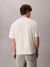 Remera Calvin Klein de color beige, corte relajado y manga corta, con cuello mock y gráfico abstracto de logo en bloque en el pecho.