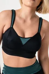 Bralette deportivo reductor negro con breteles anchos magenta regulables y escote alto. Confeccionado en jersey y tela de faja de alta contención.