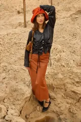 Falda larga de cuero genuino en color mostaza, con diseño de tiro bajo y silueta recta. Presenta bolsillos funcionales delanteros y traseros, cierre con botón y múltiples tajos que aportan movimiento y comodidad.