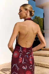 Vestido midi bordó de Lady Pipa, con estampado floral en tonos rojos y celestes, cuello halter fruncido, diseño sin mangas con espalda descubierta y detalle fruncido en la cintura y cadera.