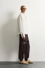 Pantalón cargo de corte ajustado en color negro, confeccionado en tejido de algodón con elasticidad. Presenta cintura elástica con cordón ajustable, bolsillos laterales tipo cargo con solapa y bajo con puños elásticos.